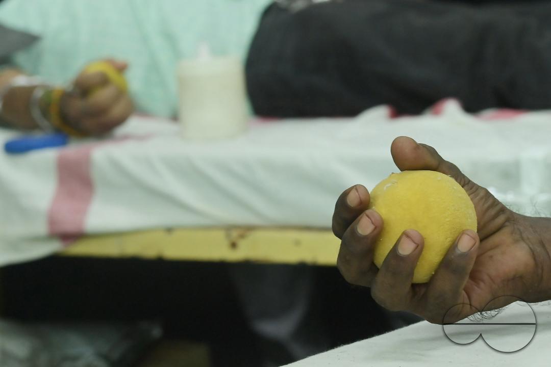 A man squeezes a sponge ball as he donates blood on World Blood Donor Day at a blood donation centre in Agartala