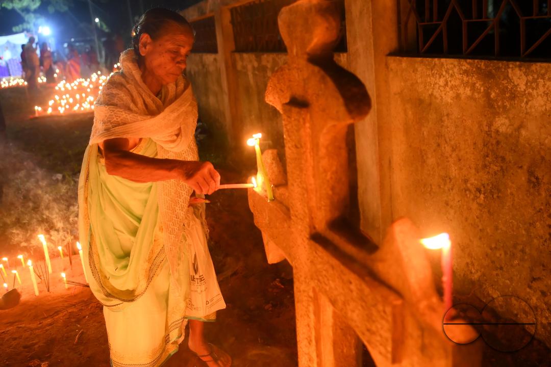 Christians offer prayers next to the graves of their family members at a cemetery during "All Souls Day" on the outskirts of Agartala