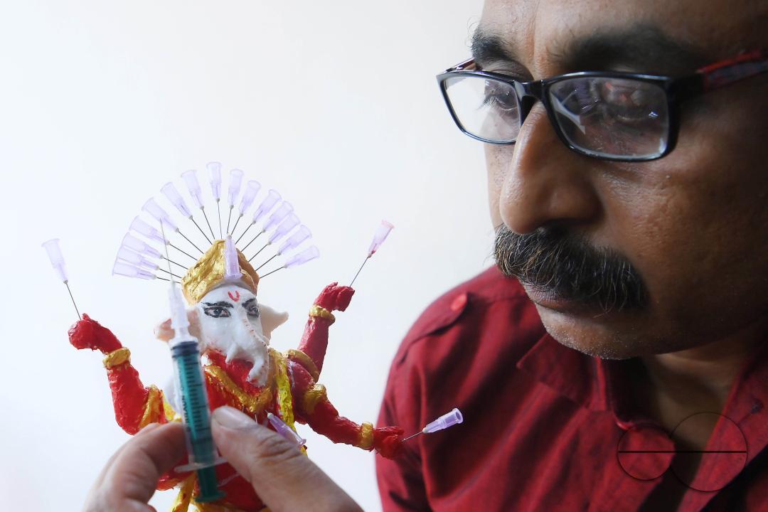 Samiran De, an artist works on an idol of Lord Ganesha made with soup and syringe needles to alert people against drugs, ahead of Ganesh Chaturthi festival, in Agartala