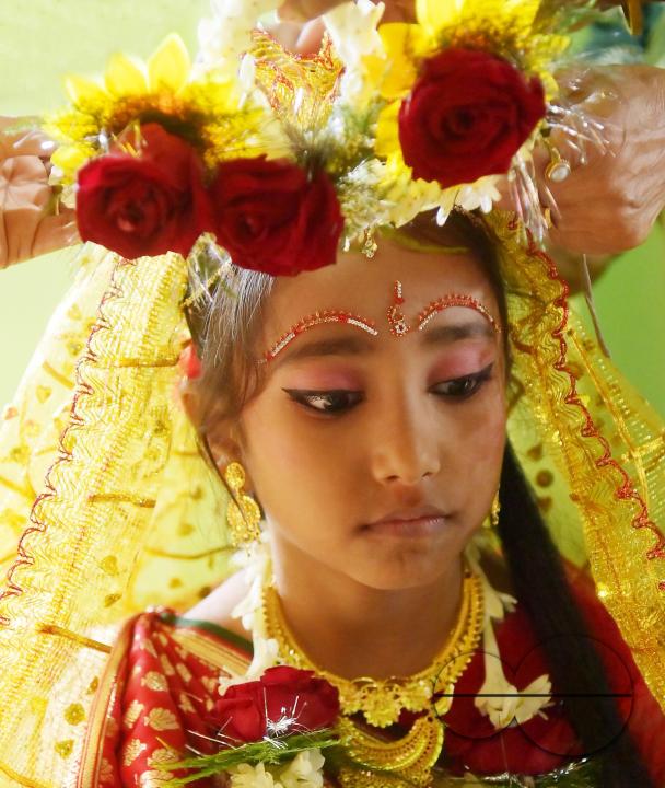 Devotees prepare the nine-year, five-month, and fourteen-day-old Hindu girl Debalina Chakraborty, known as a "Kumari," as she yawns while awaiting worship by priests during Durga Puja at the Ramakrishna Vivekananda Ashram