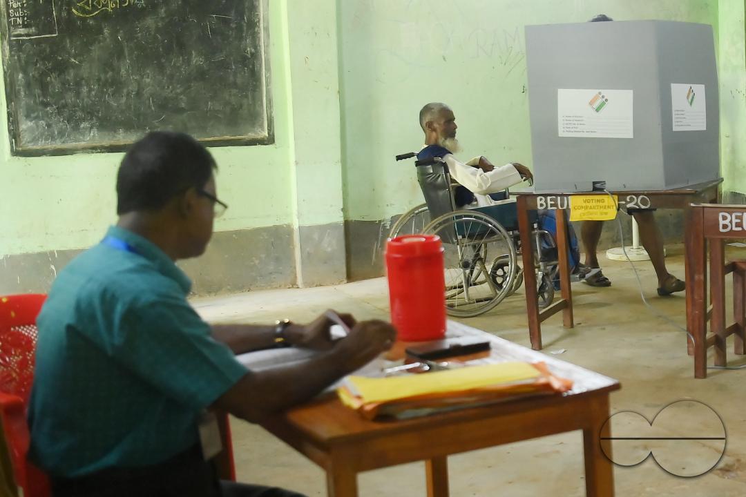 An elderly disabled voter at a polling station with the helper during the by-elections for the Boxonagar assembly seat, in Tripura Sepahijala district