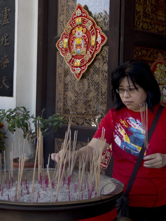 Woman paying respect at a temple on the eve of Chinese New Year in Singapore