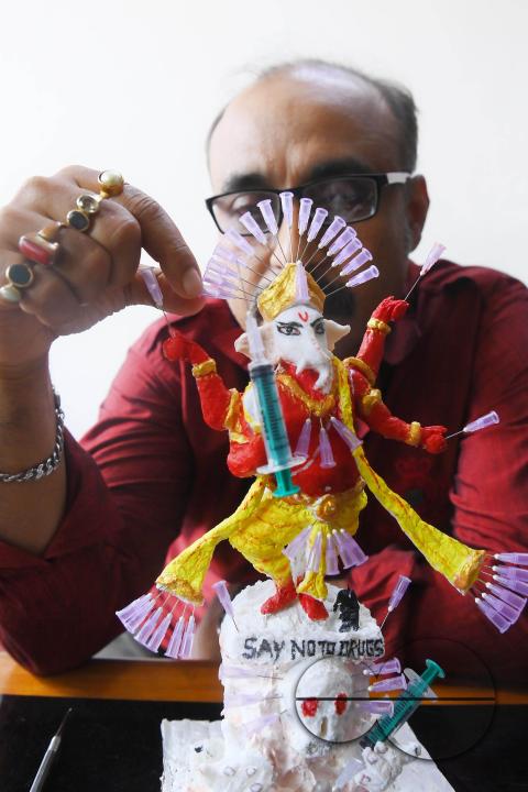 Samiran De, an artist works on an idol of Lord Ganesha made with soup and syringe needles to alert people against drugs, ahead of Ganesh Chaturthi festival, in Agartala