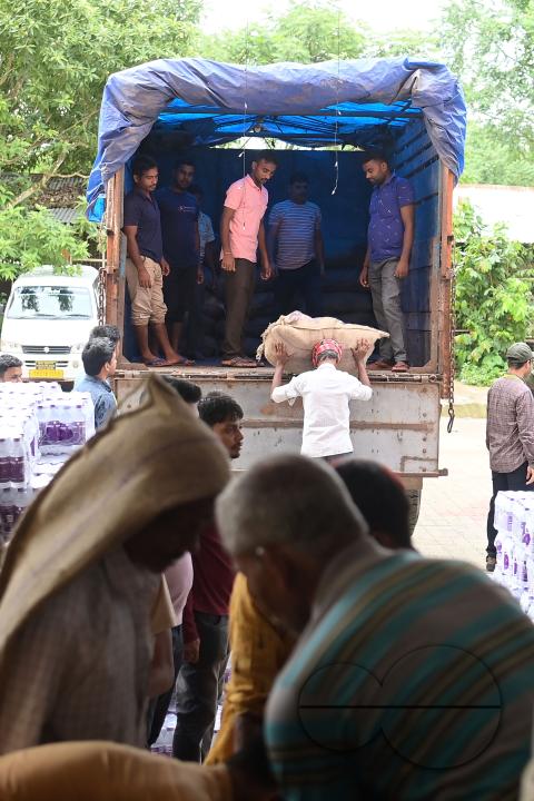 Laborers are carrying packets of food and stacking them in a truck as government officials and workers prepare food packets to be distributed by NDRF (National Disaster Response Force) personnel from helicopters to flood victims in different parts of Tri