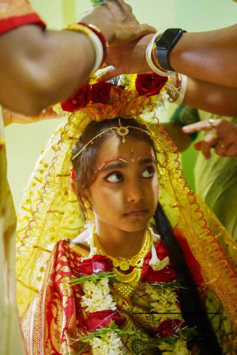 Devotees prepare the nine-year, five-month, and fourteen-day-old Hindu girl Debalina Chakraborty, known as a "Kumari," as she yawns while awaiting worship by priests during Durga Puja at the Ramakrishna Vivekananda Ashram
