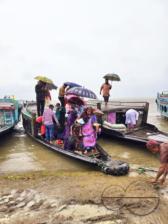 Passengers embarking and disembarking, in the tropical rain, from country launches which are berthed at the shore of Dingapotha, Mohonganj âhaorâ (a large body of wetland formed by river and rain water, famous as a fishing area)