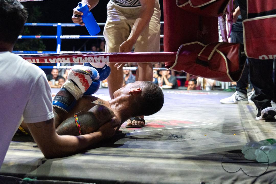The trainer and a helper is giving water to his boxer Petch Si Nel, at the center, after a knockout, during the Muay Thai Fights, on Koh Chang Island, Thailand.
