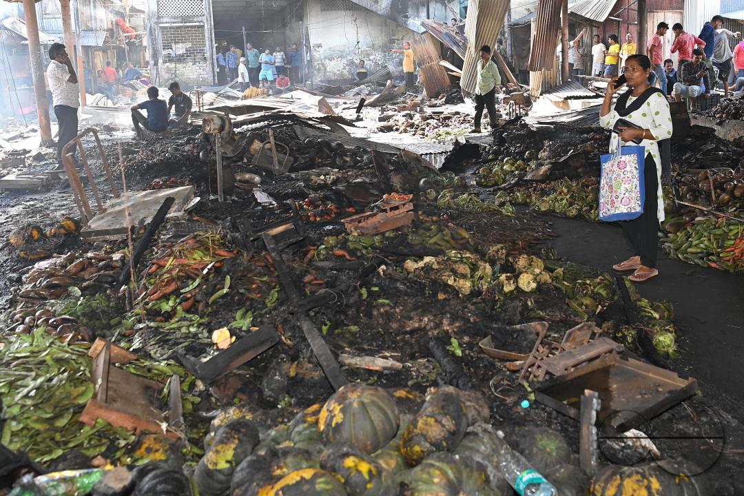 Shop owners and vendors are seen in front of their burnt shops and vegetables stalls in Battala market, the second biggest market in Tripura