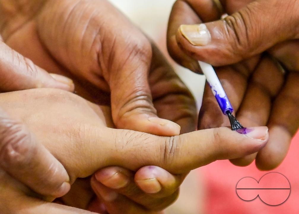 An election official marking the finger of a differently abled boy before casting his postal ballot vote with the assistance of her family members at her house in front of the team of election officials and security personnel in Agartala