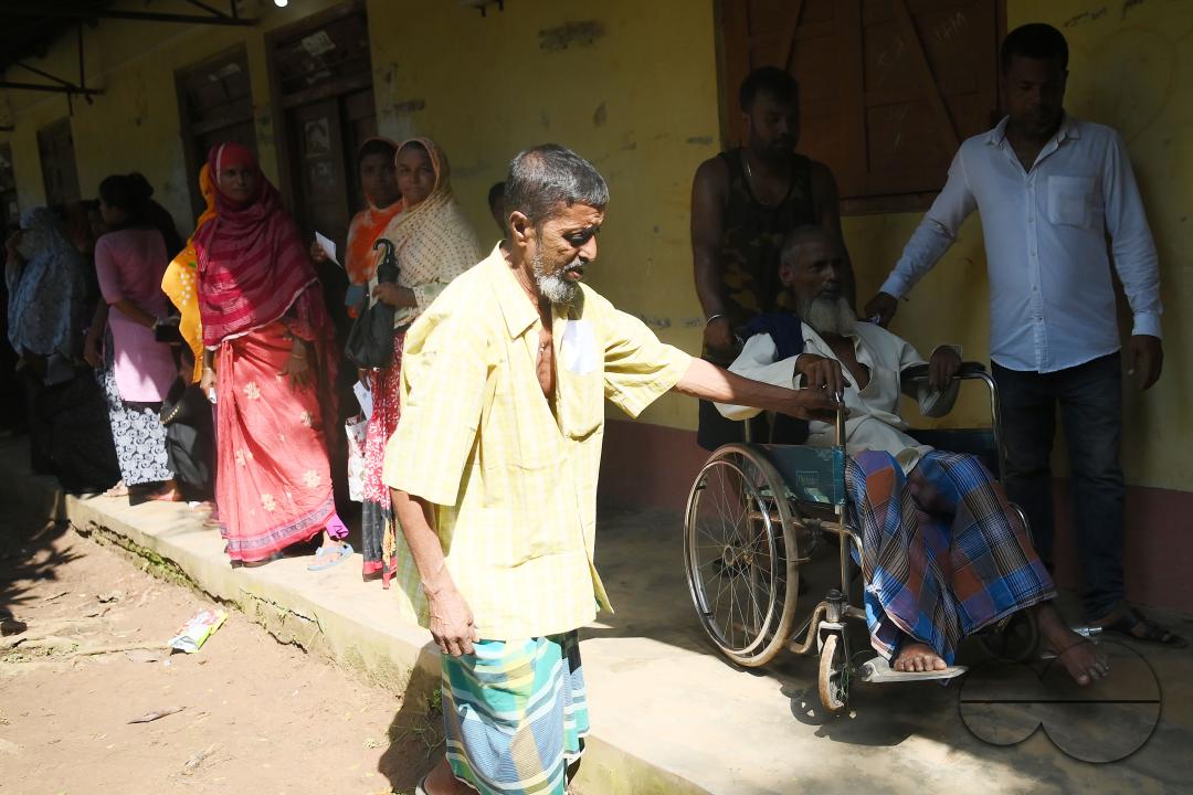 An elderly disable voter coming out from polling station with the help of volunteers after casting his vote during the by-elections for the Boxonagar assembly seat, in Tripura Sepahijala district