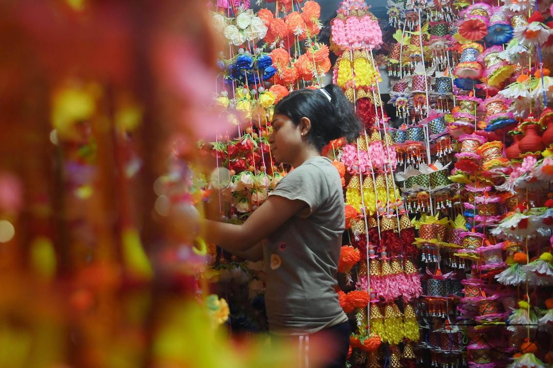 A worker arranging plastic garlands for sale at a stall ahead of the festive