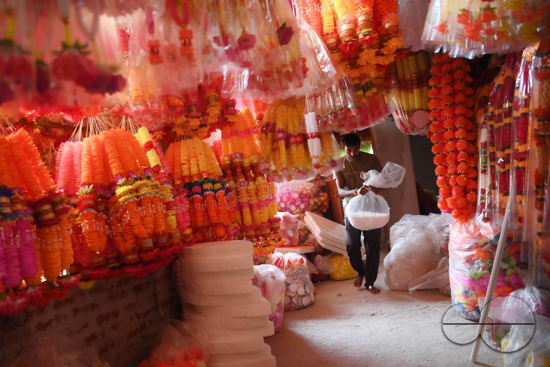 A worker arranging plastic garlands for sale at a stall ahead of the festive