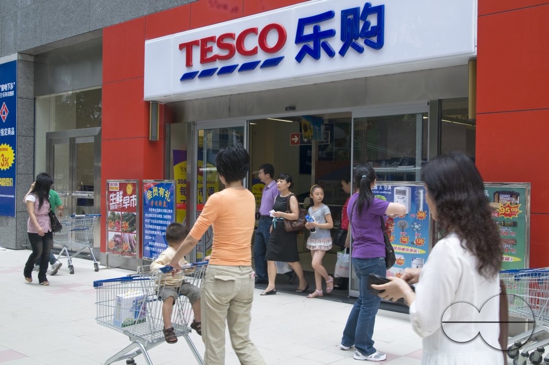 CHINA Shoppers walking past a Tesco store in Guangzhou, Guangdong province.