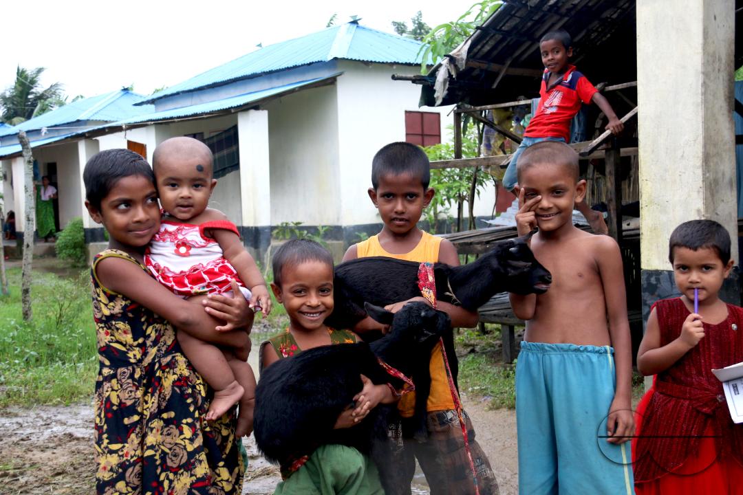 Rural Bangladeshi children happily playing in the neighborhood with goats