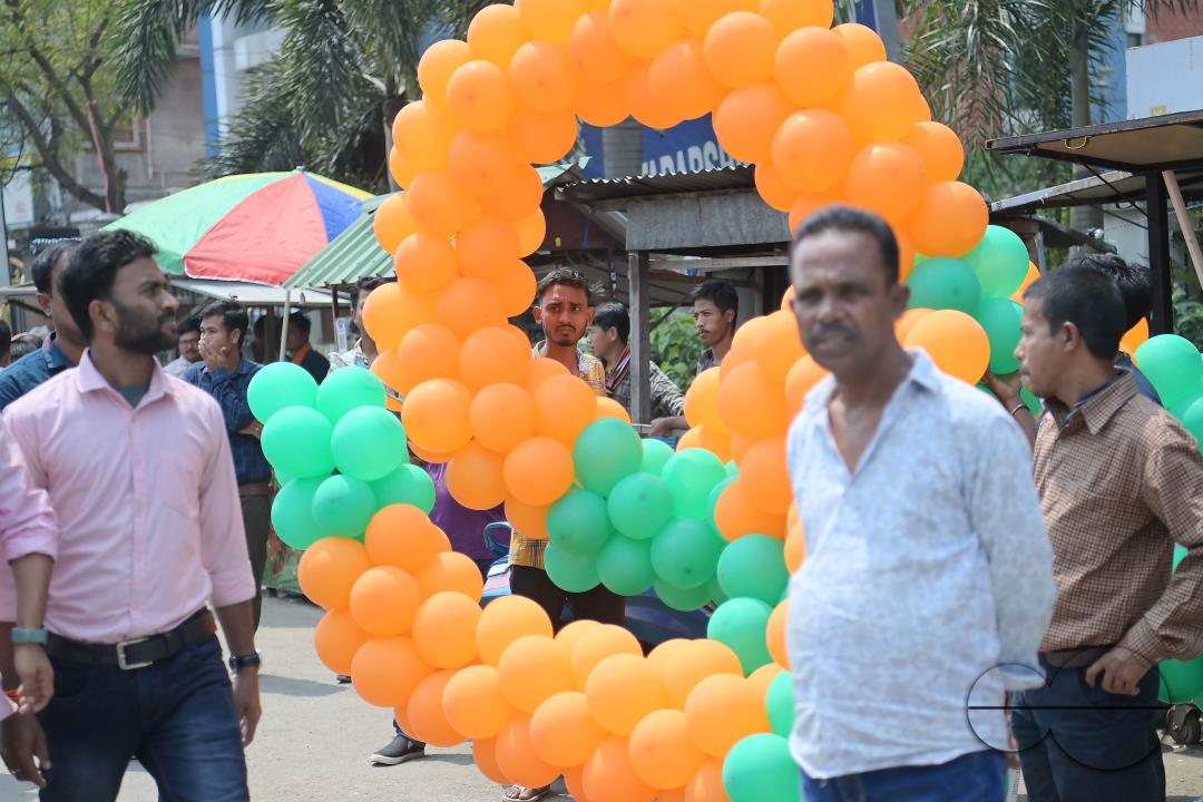 Supporters of the BJP are seen decorating balloons in the party's colours at a rally featuring Tripura Chief Minister Manik Saha, former CM and BJP candidate Biplab Kumar Deb, and Kriti Singh, alongside other leaders, during an election campaign rally in