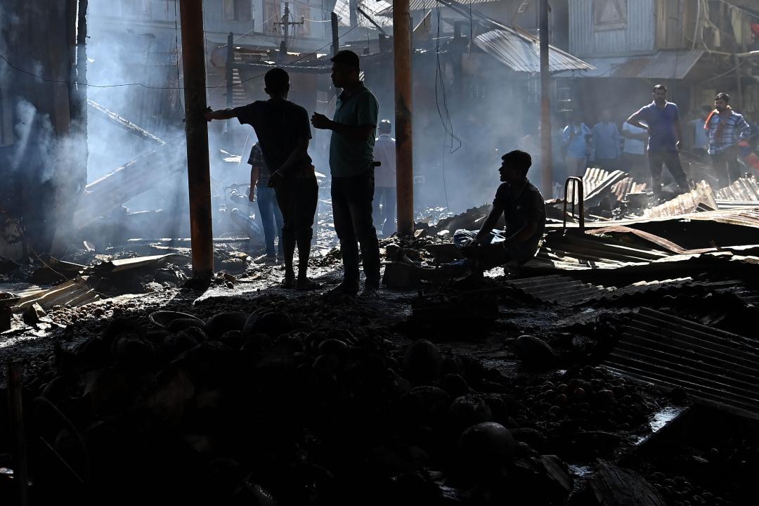 Shop owners and vendors are seen in front of their burnt shops and vegetables stalls in Battala market, the second biggest market in Tripura