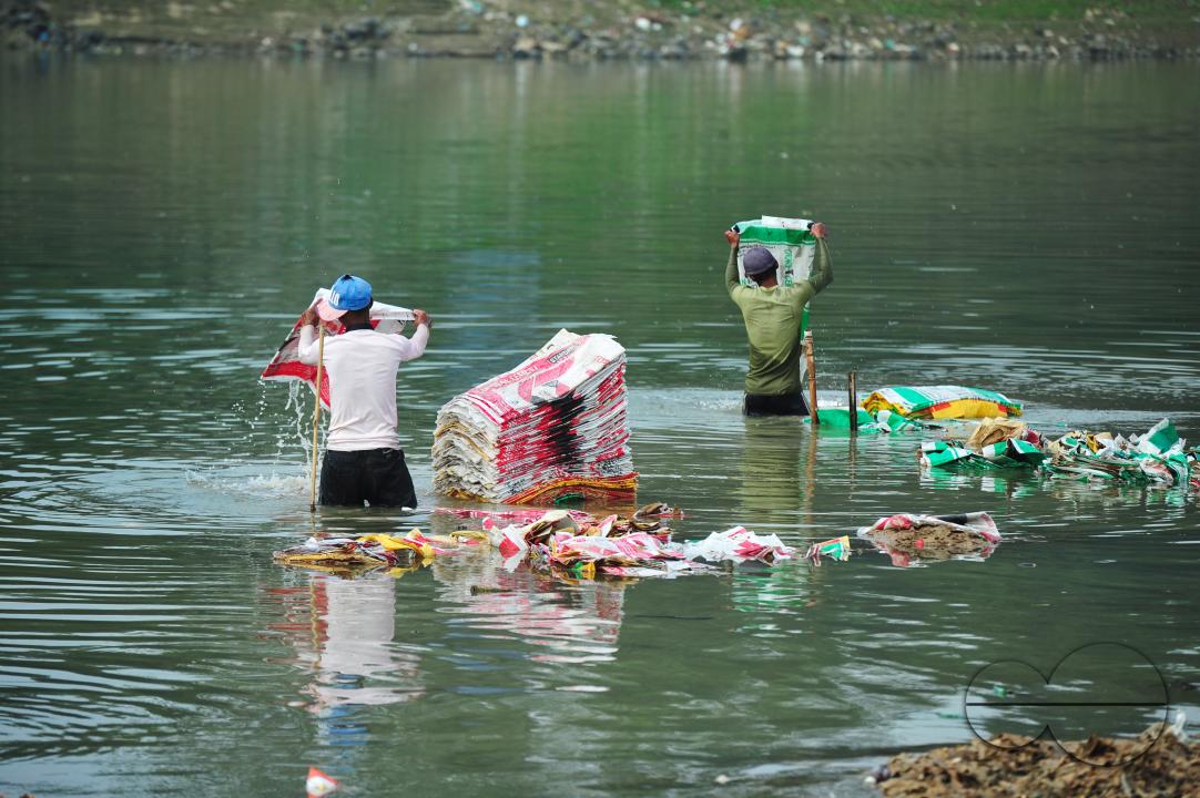 Women are risking their lives to wash cement bags beside the Surma River in Sylhet