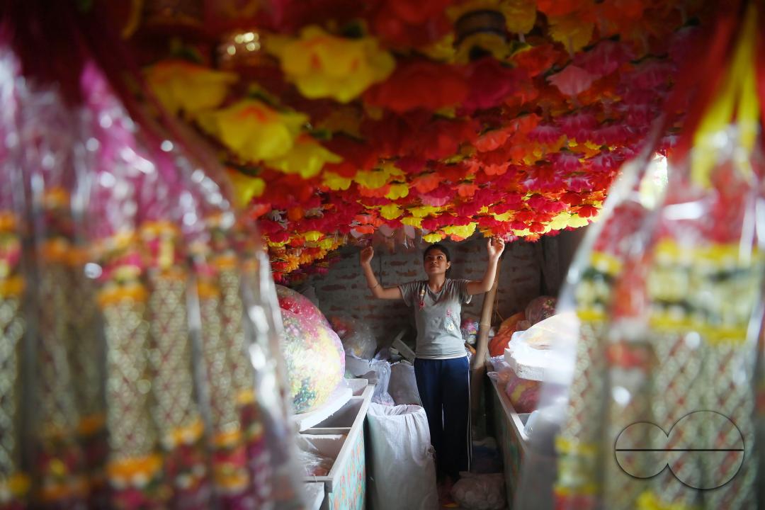 A worker arranging plastic garlands for sale at a stall ahead of the festive