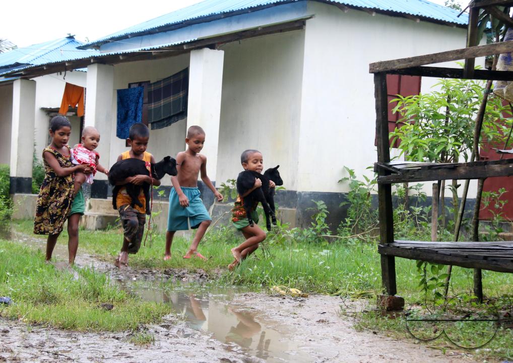 Rural Bangladeshi children happily playing in the neighborhood with goats