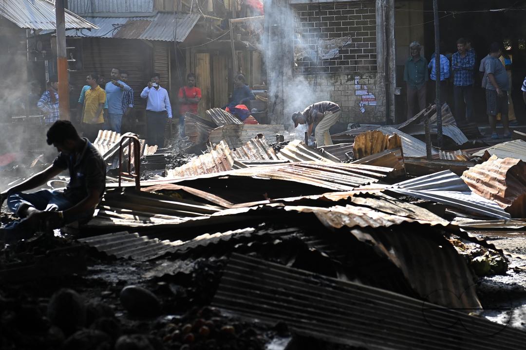 Shop owners and vendors are seen in front of their burnt shops and vegetables stalls in Battala market, the second biggest market in Tripura