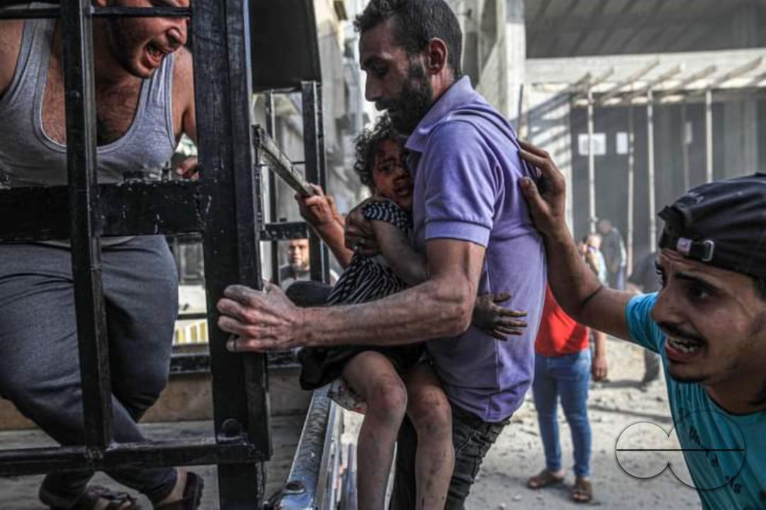 A Palestinian father tries to evacuate a family, most of which were injured in an Israeli air strike on the Al-Zaytoun neighborhood, east of Gaza City