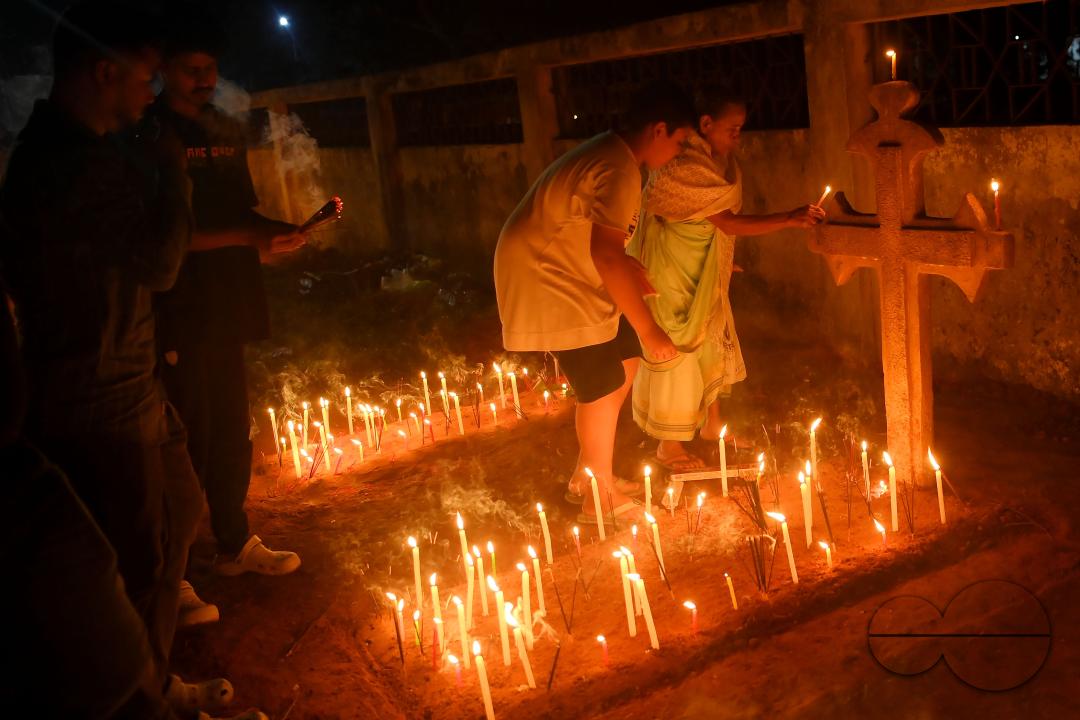Christians offer prayers next to the graves of their family members at a cemetery during "All Souls Day" on the outskirts of Agartala