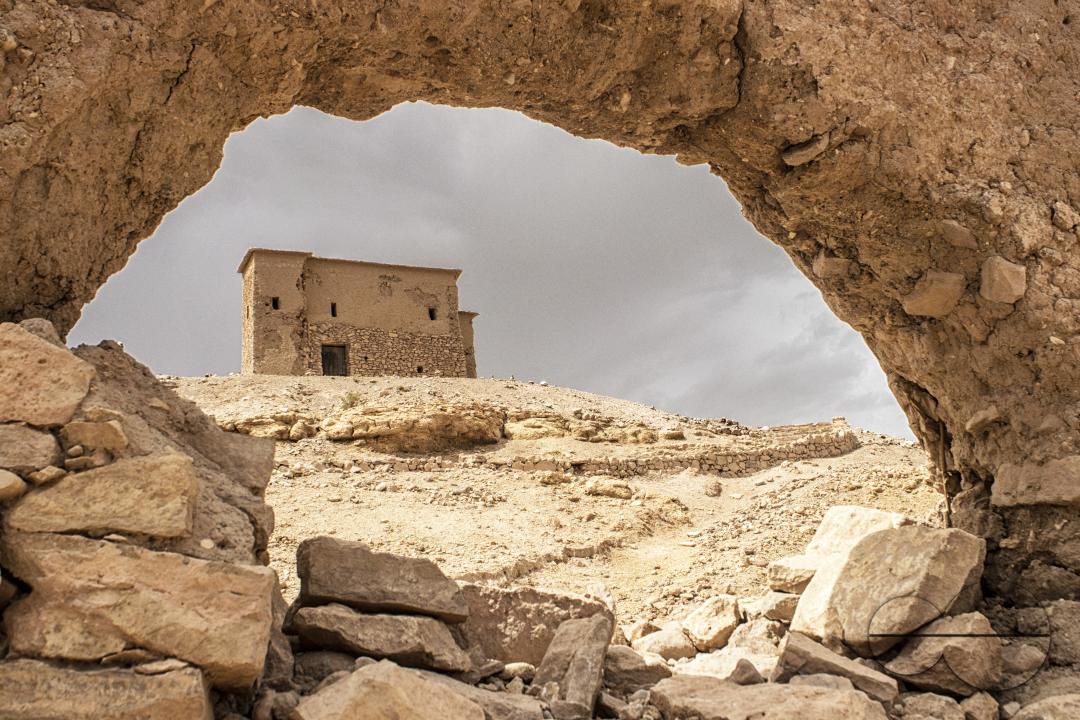 A desert building framed by a stone wall in Merzouga, a small Moroccan town in the Sahara Desert, near the Algerian border