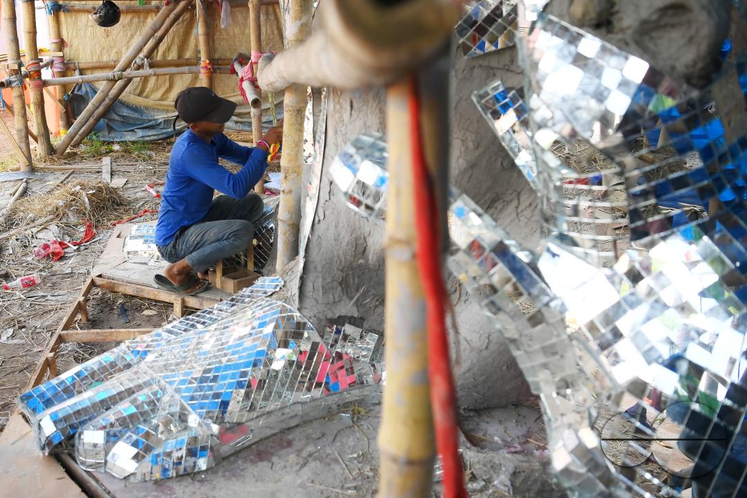 An artist is pasting glass pieces to make a 41 feet tall Ganesh idol, fully covered by glass, ahead of Ganesh Chaturthi festival in a pandal in Ranir bazar