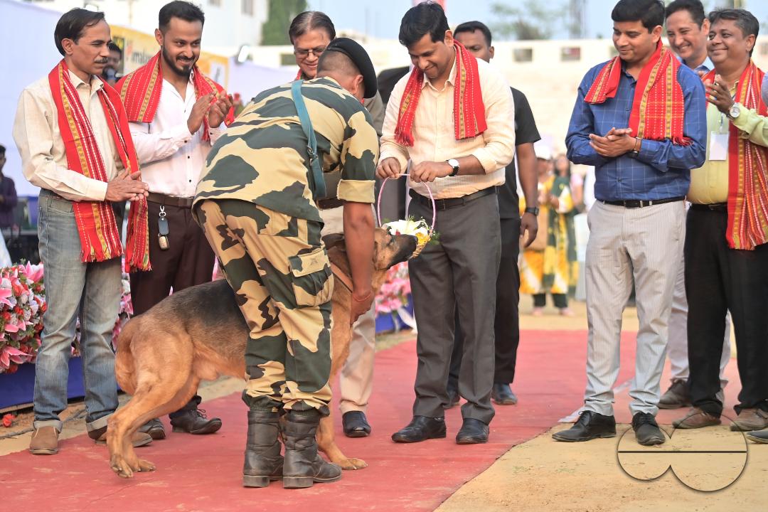 Minister of Animal Resource Development of Tripura, Sudhanshu Das receives a flower bouquet from a trained dog of BSF (Border Security Force of India), on the inauguration of Agartala Dog Carnival-2024, organized by the Tripura Veterinary Doctors Associa
