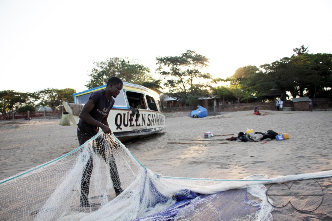 A man is preparing fishing nets at sunset in Senga Bay, Malawi