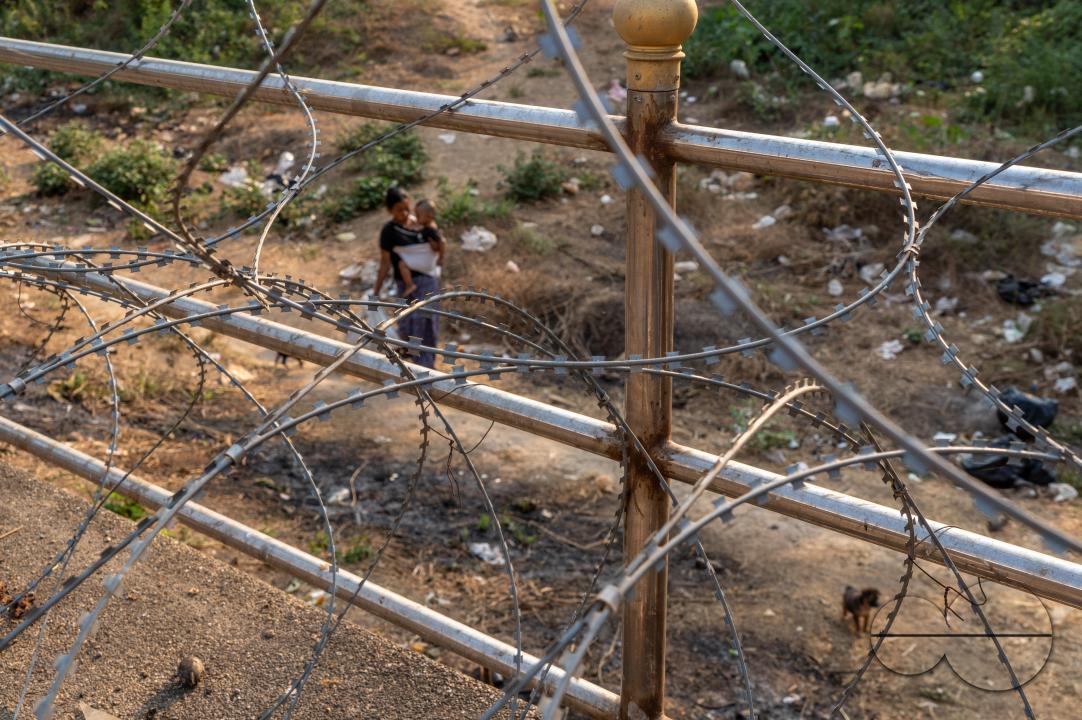 Visitors, traders and illegal Burmese immigrants walk by barbed wire at the Thai side of the Thailand - Myanmar border at Mae Sot, Thailand.