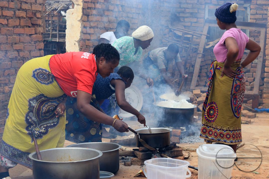 Women are seen manning pots on open fires as they prepare food for a party in Mchinji District