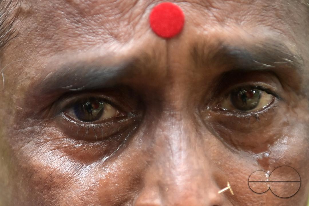 An elderly woman is crying in front of local MLAS officials at her makeshift tent at the Panisagar's reserve forest