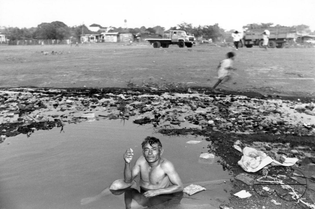 NICARAGUA A REFUGEE FROM THE WAR ZONES HAVING A BATH IN A DIRTY POOL, DOWNTOWN MANAGUA,1990