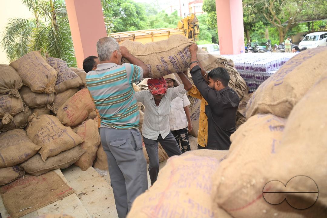 Laborers are carrying packets of food and stacking them in a truck as government officials and workers prepare food packets to be distributed by NDRF (National Disaster Response Force) personnel from helicopters to flood victims in different parts of Tri