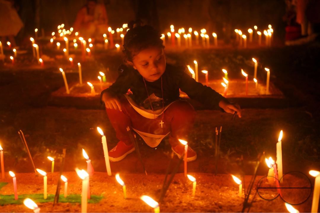 Christians offer prayers next to the graves of their family members at a cemetery during "All Souls Day" on the outskirts of Agartala