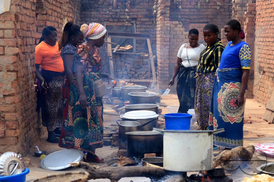 Women are seen manning pots on open fires as they prepare food for a party in Mchinji District