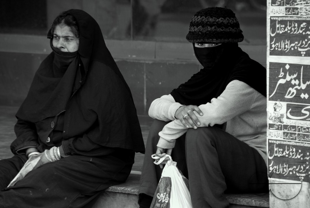 Two women sitting near the market area, Lahore.
