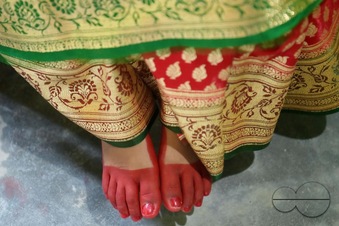 Devotees cover the feet of the nine-year, five-month, and fourteen-day-old Hindu girl, Debalina Chakraborty, with "Alta," a red dye applied to the hands and feet of women during worship and festivals