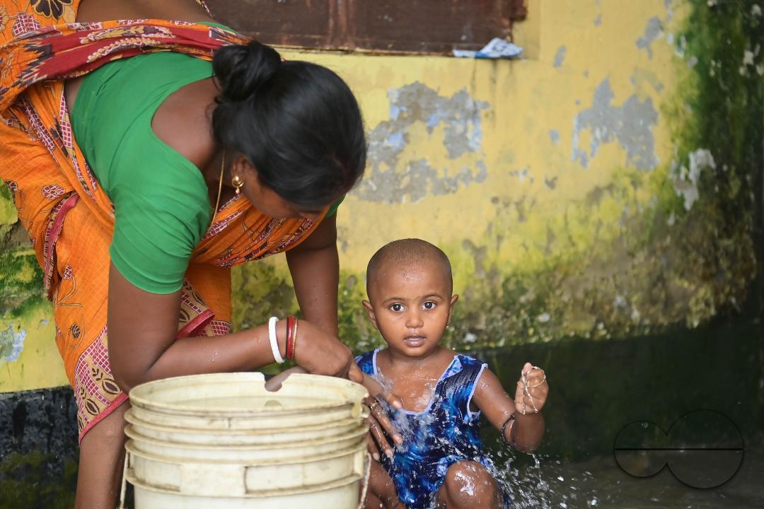 A mother is bathing her son at a temporary relief camp at Pratapgarh English Medium School in Agartala