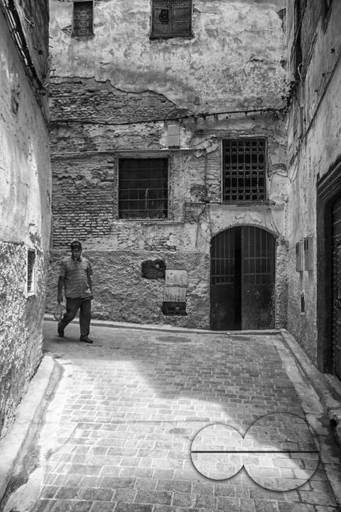 A man walking along the narrow medina streets of Fez