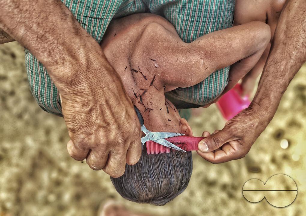 A man cutting a kids hair at the Balukhali refugee camp