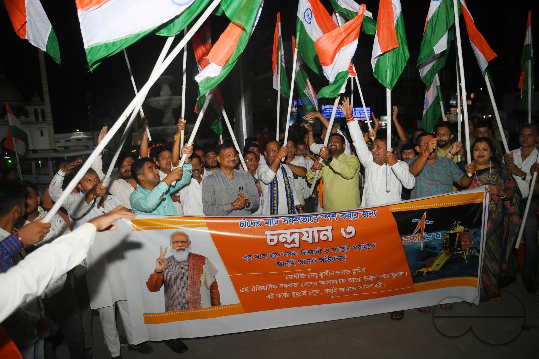 BJP party leaders, workers and the general public celebrate with the Indian flag in front of a LCD TV during the live stream of the successful lunar landing of the Chandrayaan-3 spacecraft on the south pole of the Moon, in Agartala