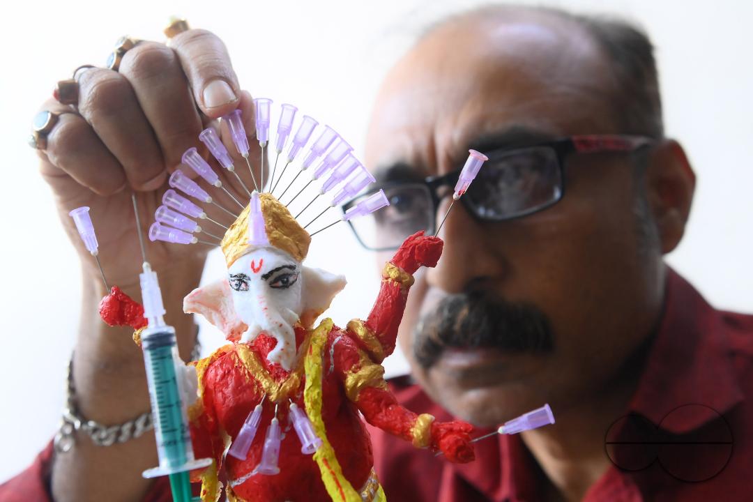 Samiran De, an artist works on an idol of Lord Ganesha made with soup and syringe needles to alert people against drugs, ahead of Ganesh Chaturthi festival, in Agartala
