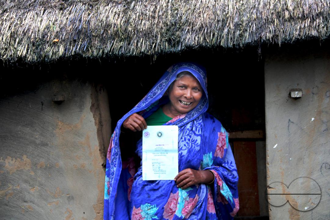 Portrait of a rural Bangladeshi woman showing her accommodation and old age allowances which are donated by the government