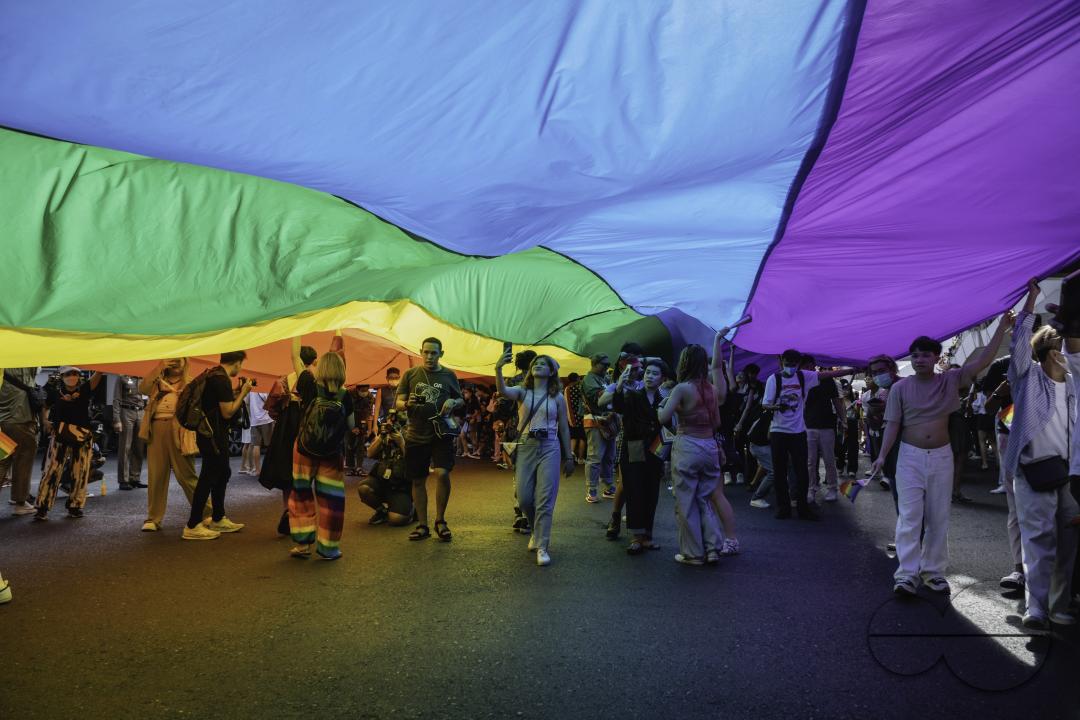People carrying a rainbow flag above their heads which is the gay pride flag symbol of lesbian, gay, bisexual, and transgender (LGBT) pride and LGBT social movements, at Bangkok Pride Parade 2023 in Bangkok, Thailand.