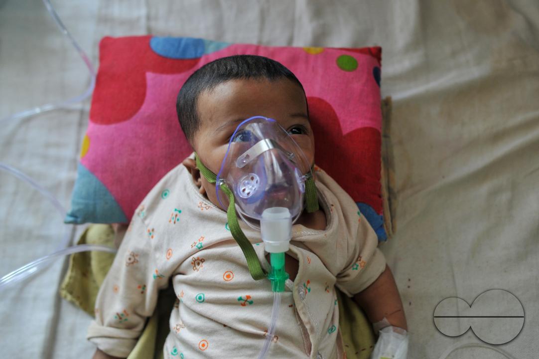 A senior nurse is providing medical care to a child in Sylhet MAG Osmani Medical College Hospital