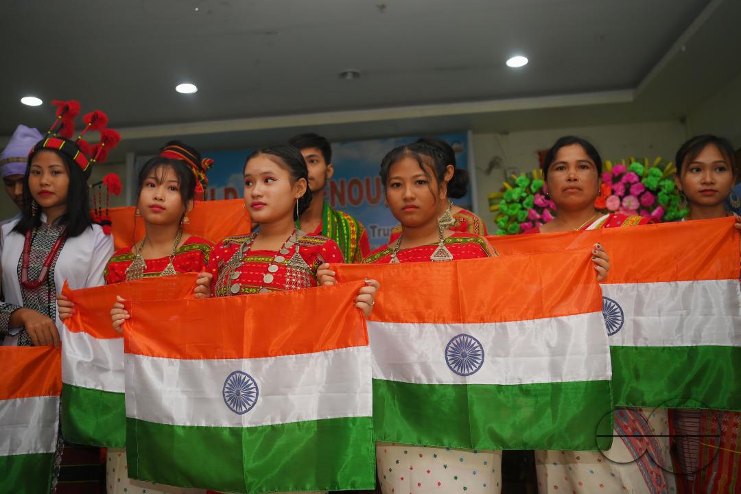 Indigenous girls holding the national flag during a cultural program on the occasion of World Indigenous Day at an auditorium in Agartala