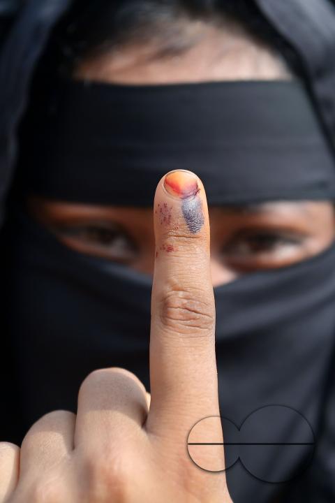 A muslim woman proudly displays her inked finger after voting in the first phase of Lok Sabha elections at a polling station in Agartala