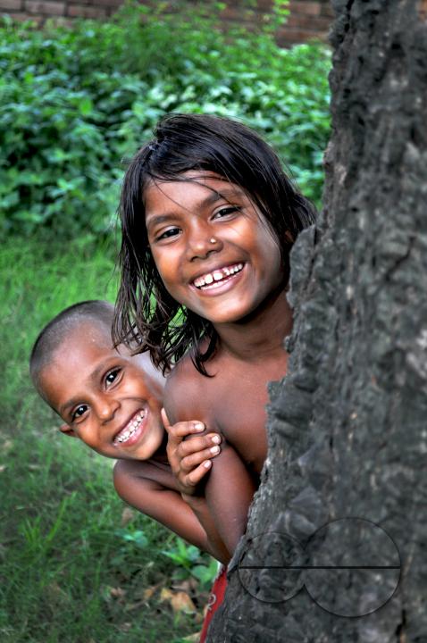 Portrait of two children playing hide and seek in the slums of Rayer bazar